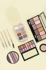 Eyeshadows with brushes on yellow background