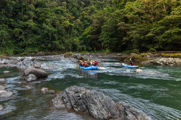 group of tourists rafting on a raft and kayak in the middle of the jungle on the Pacuare River in Costa Rica - obrazy, fototapety, plakaty