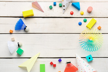 Frame made of baby toys and party hats on white wooden background. Children's Day celebration
