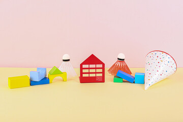 Fototapeta premium House figure with toys and party hat on table near pink wall. Children's Day celebration
