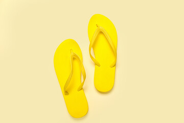 Yellow flip-flops on beige background, top view