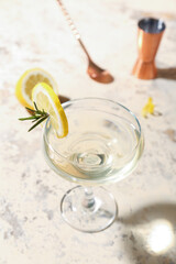 Glass of tasty martini and lemon on light grunge background
