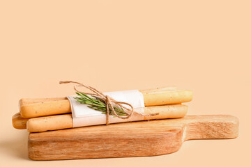 Wooden board with bunch of tasty Italian Grissini on yellow background