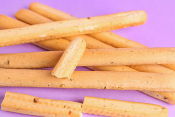 Tasty Italian Grissini on lilac background, closeup