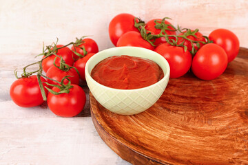Bowl with tasty tomato paste and fresh vegetables on light wooden background