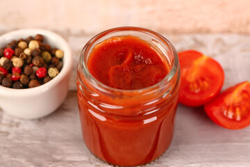 Jar with tasty tomato paste on light wooden background, closeup