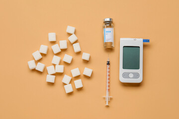 Glucometer with insulin, syringe and sugar on orange background. Diabetes concept