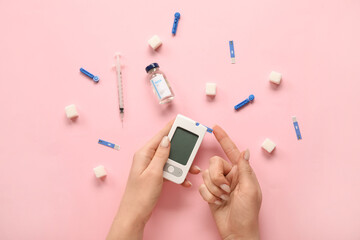 Woman using glucometer on pink background. Diabetes concept