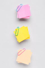 Beige, yellow and pink sticky notes with paper clips on grey background