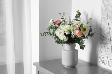 Bouquet with beautiful flowers on light gray chest of drawers indoors. Space for text