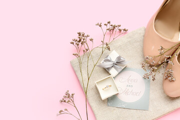 Box with engagement ring, flowers, heels and wedding invitation on pink background