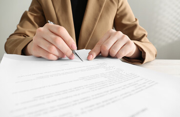 Woman signing document at table, closeup view