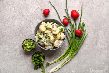 Bowl of tasty Potato Salad with greens on grey background
