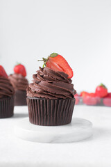 Chocolate cupcake with dark chocolate buttercream and strawberries, double chocolate cupcakes with american buttercream, tall swirl frosting on a cupcake with a strawberry
