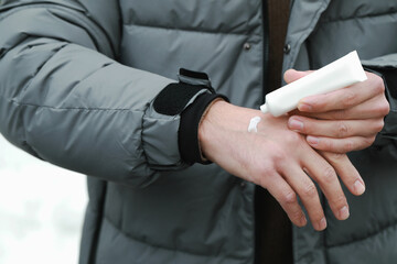 Man applying cream from tube onto hand, closeup. Winter care