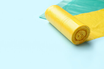 Yellow roll of garbage bags on blue background, closeup