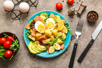Plate of tasty potato salad with eggs and avocado on grey background, top view