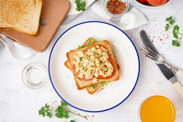 Plate with tasty scrambled eggs sandwich on table