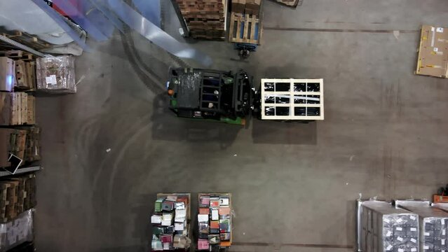 Top down view of forklift transporting pallet in retail logistic center warehouse 
