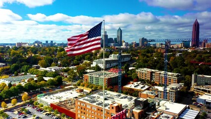 Aerial drone shot slowly rotating around an American Flag hoisted above Ponce City Market with downtown Atlanta Georgia in the background.