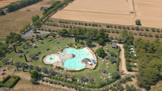 Drone shot orbiting large outdoor swimming pool at holiday resort