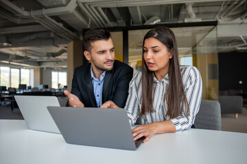 Young latin couple working using laptop sitting on the table at home.