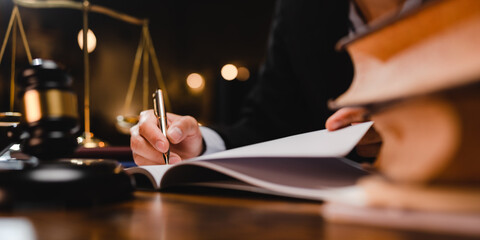 businessman or legal expert reviewing document reports at office workplace with computer laptop, professional lawyer reading and checking financial documents or insurance and sign a contract by pen