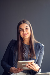 Young attractive female manager working on digital tablet while standing in modern office