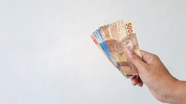 Man's Hand holding rupiah money isolated on white background