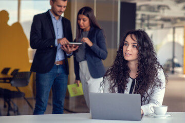 Confident attractive young business woman with tablet in hands in modern office start up office