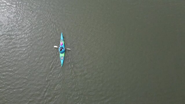woman paddling a kayak through the sea in england from the birds eye view of a drone