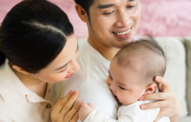 Smiling mother and father holding newborn son at home