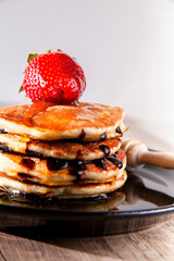 A stack of pancakes with fresh strawberry, honey on top a white wooden background. A healthy breakfast. Copy space