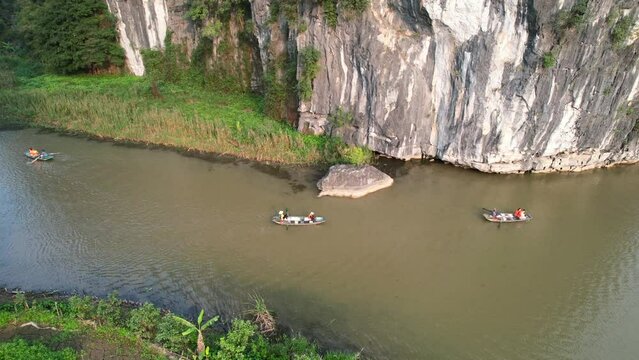 People enjoy trip on sampan boats on Ngo Dong river in Picturesque Limestone valley landscape in Ninh Binh Vietnam -  aerial panning