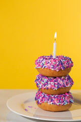 Stack of colorful sprinkle birthday donuts