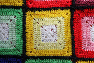 Close up of a yellow, red and green crocheted woollen blanket