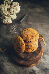 Homemade chocolate chip cookies on rustic wooden coaster and abstract background