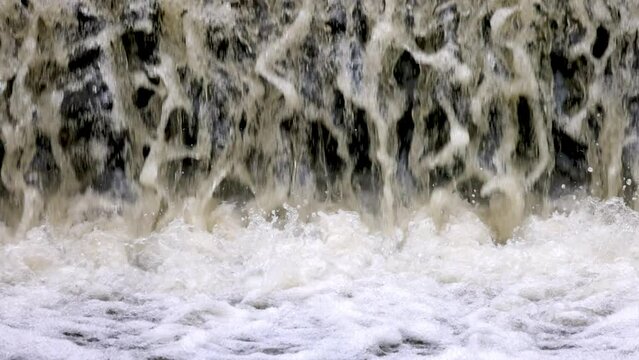 Water gushes and splashes down small waterfall into turbulent pool