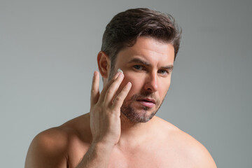 Close up portrait of man 40s applying cream on face. Handsome serious man enjoy fresh perfect skin, applying cream. Portrait of beauty man with cosmetic cream on skin. Facial treatment. male beauty.