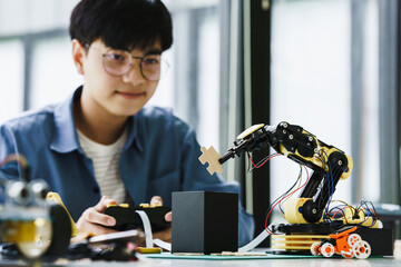 Asian teenager students doing or playing robot arm and robotic cars homework project in house assemble the circuit and coding. technology of robotics programing and STEM education concept