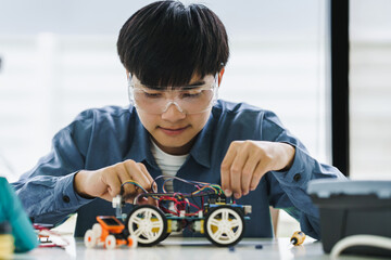 Asian teenager students doing robot arm and robotic cars homework project in house assemble the...