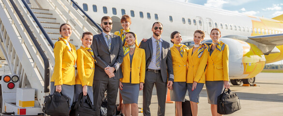 Cheerful aircrew standing near airplane at airport