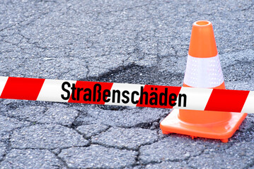 Ein Schlagloch in der Straße und Warnung vor den Straßenschäden