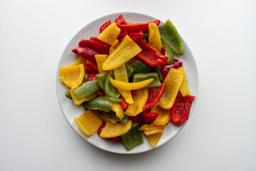 Fresh colored pepper salad in a white dish. Top view