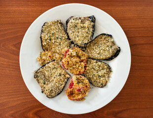Gratinated pepper in a white dish on wooden table. Top view
