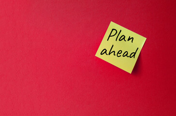 Plan ahead symbol. Orange steaky note with words Plan ahead. Beautiful red background. Business and Plan ahead concept. Copy space.
