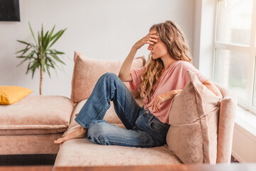 Sad woman thinking about problem, sitting alone on couch