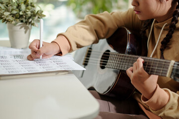 Girl writing down music notes when composing song