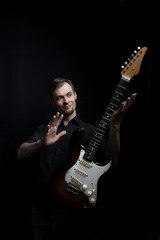 The guitarist masterfully controls the electric guitar, studio portrait on a black background.