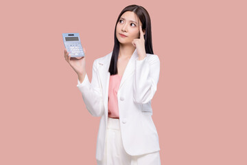 Young Asian woman feel confuse hold in hands calculator isolated on pastel pink background studio portrait.